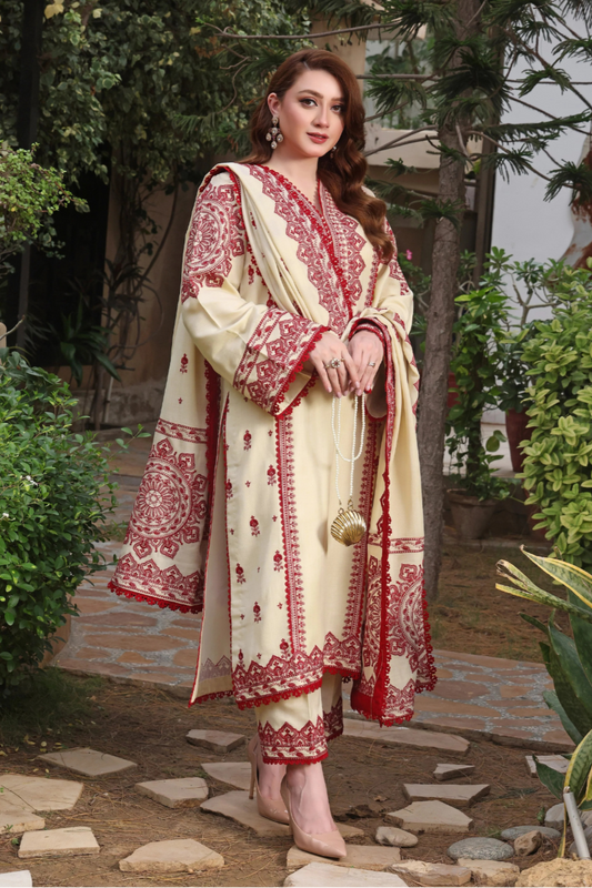 Woman in a cream and red embroidered traditional outfit standing outdoors with greenery.